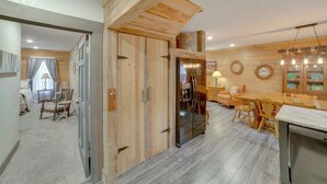 Un intérieur en bois comprenant un coin repas, une cuisine et une porte visible donnant sur une autre pièce.