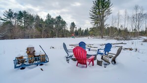 Un espace extérieur enneigé, aménagé avec des fauteuils Adirondack et un foyer.
