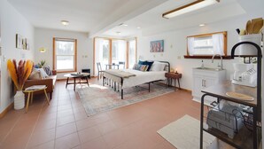 Une pièce moderne et bien éclairée, comprenant un lit, une table à manger et un coin cuisine.