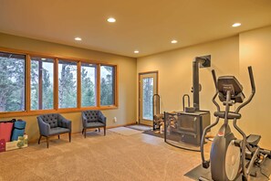 A spacious room with large windows, a treadmill, two armchairs, and a fireplace. - Expansive Hartsel Home w/ Mtn Views Near Hiking (Hartsel)