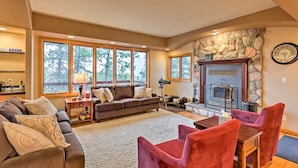 A cozy living room with a stone fireplace, a sofa, a coffee table, and a dining area with chairs. - Expansive Hartsel Home w/ Mtn Views Near Hiking (Hartsel)