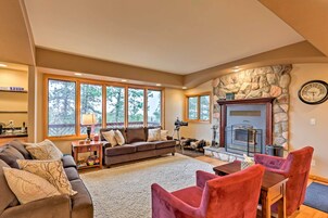 A cozy living room with a stone fireplace, a sofa, a coffee table, and a dining area with chairs.