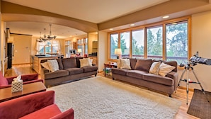 A spacious living room with a large sofa, a coffee table, and a rug. There is a kitchen area with a dining table and chairs. - Expansive Hartsel Home w/ Mtn Views Near Hiking (Hartsel)
