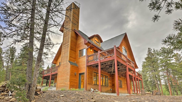 A large wooden cabin with a prominent chimney, a covered porch, and a rustic setting surrounded by trees. - Expansive Hartsel Home w/ Mtn Views Near Hiking (Hartsel)
