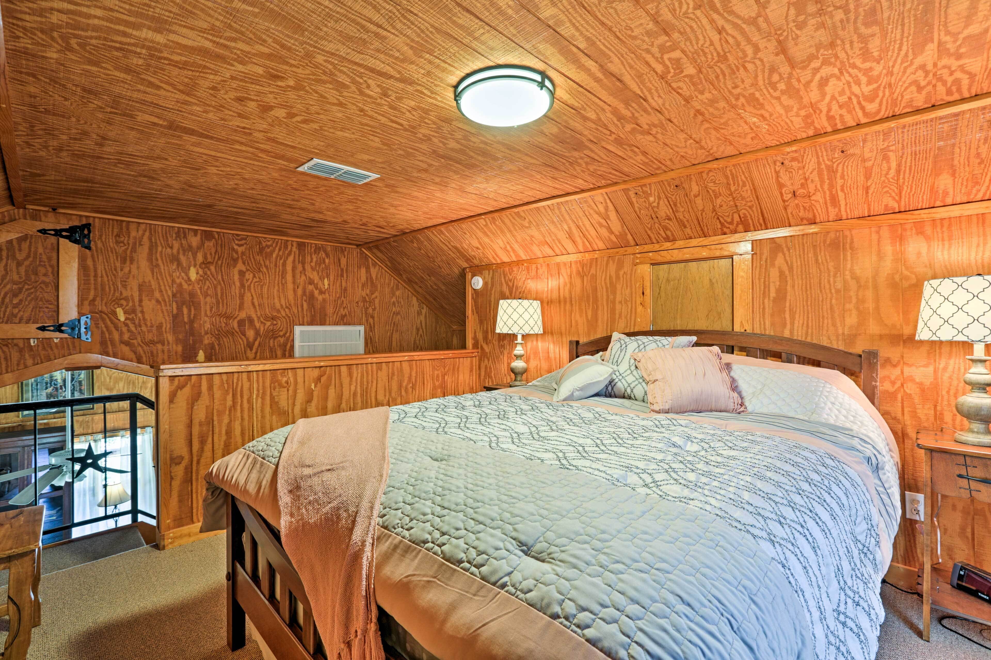 Un dormitorio con paneles de madera, una cama, lámparas de noche y un ventilador de techo.