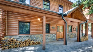 Eine Blockhütte mit Steinunterbau, einer Holzdielen-Terrasse und einer überdachten Veranda.