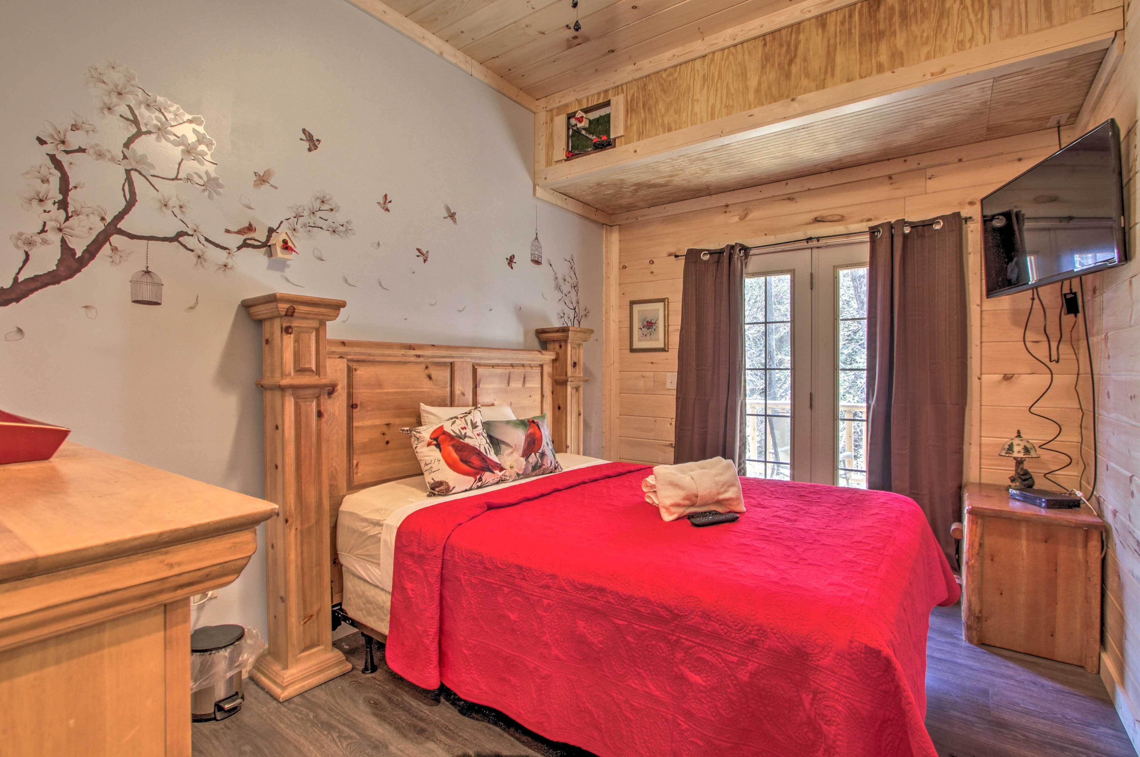 Un dormitorio de cabaña de madera con una cama, un escritorio de madera y un televisor montado en la pared.