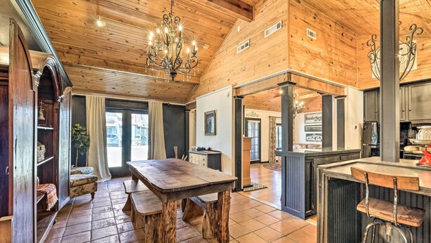 Une cuisine spacieuse avec des meubles en bois, un grand îlot central doté de tabourets et un lustre.