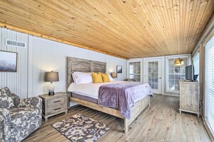 Un dormitorio con techo de madera, cama con cabecera, mesita de noche, cómoda y sofá estampado.
