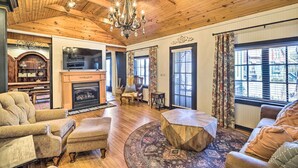 Un salon chaleureux avec une cheminée, un plafond en bois et un lustre.