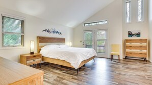 A bedroom with a wooden bed, a nightstand, a dresser, and a chair. There are two windows and a door with a view of greenery outside. - Family Getaway < 2 Mi to Massanutten Ski Lodge! (McGaheysville)