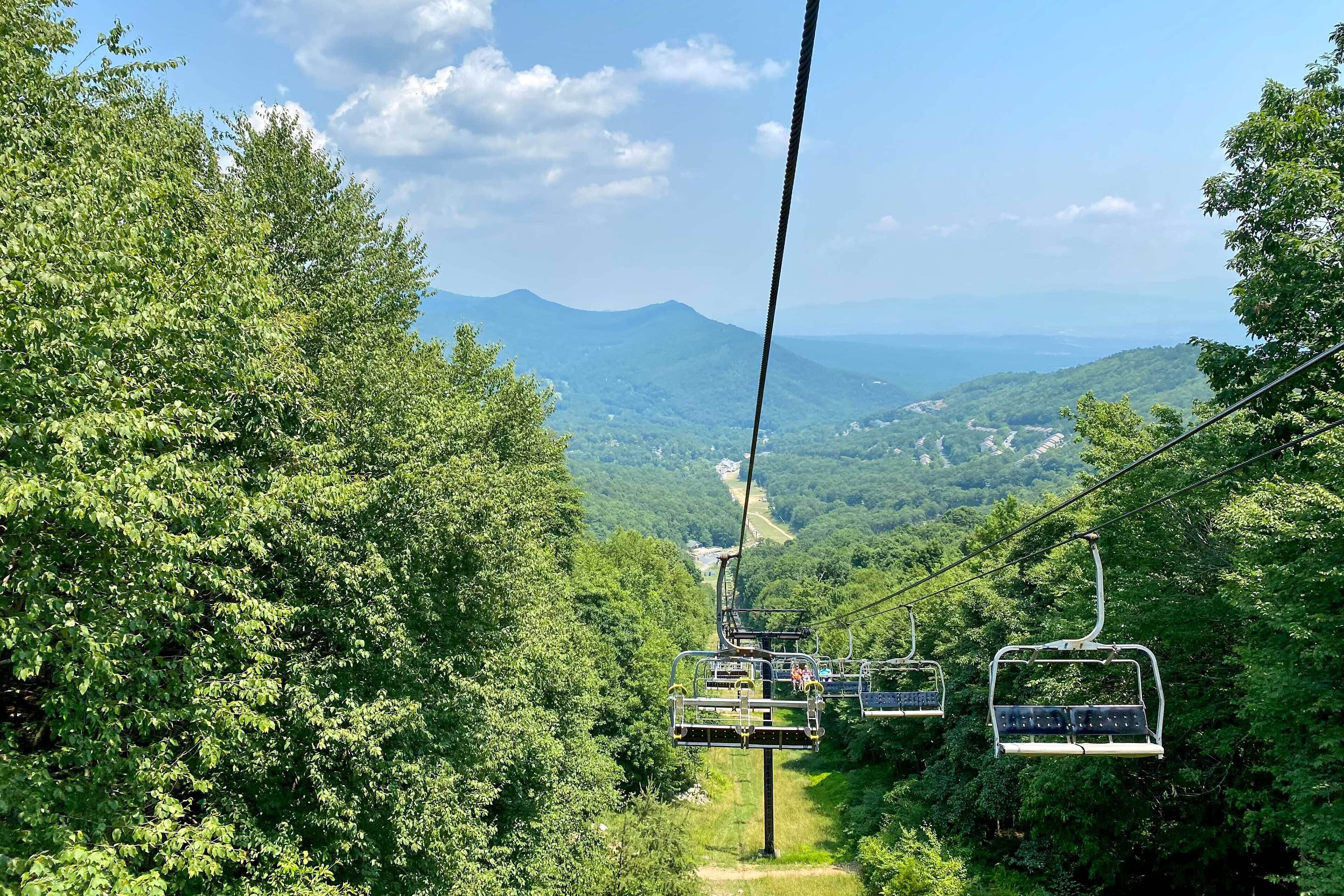 A cable car system with a clear view of the surrounding forest and distant mountains.