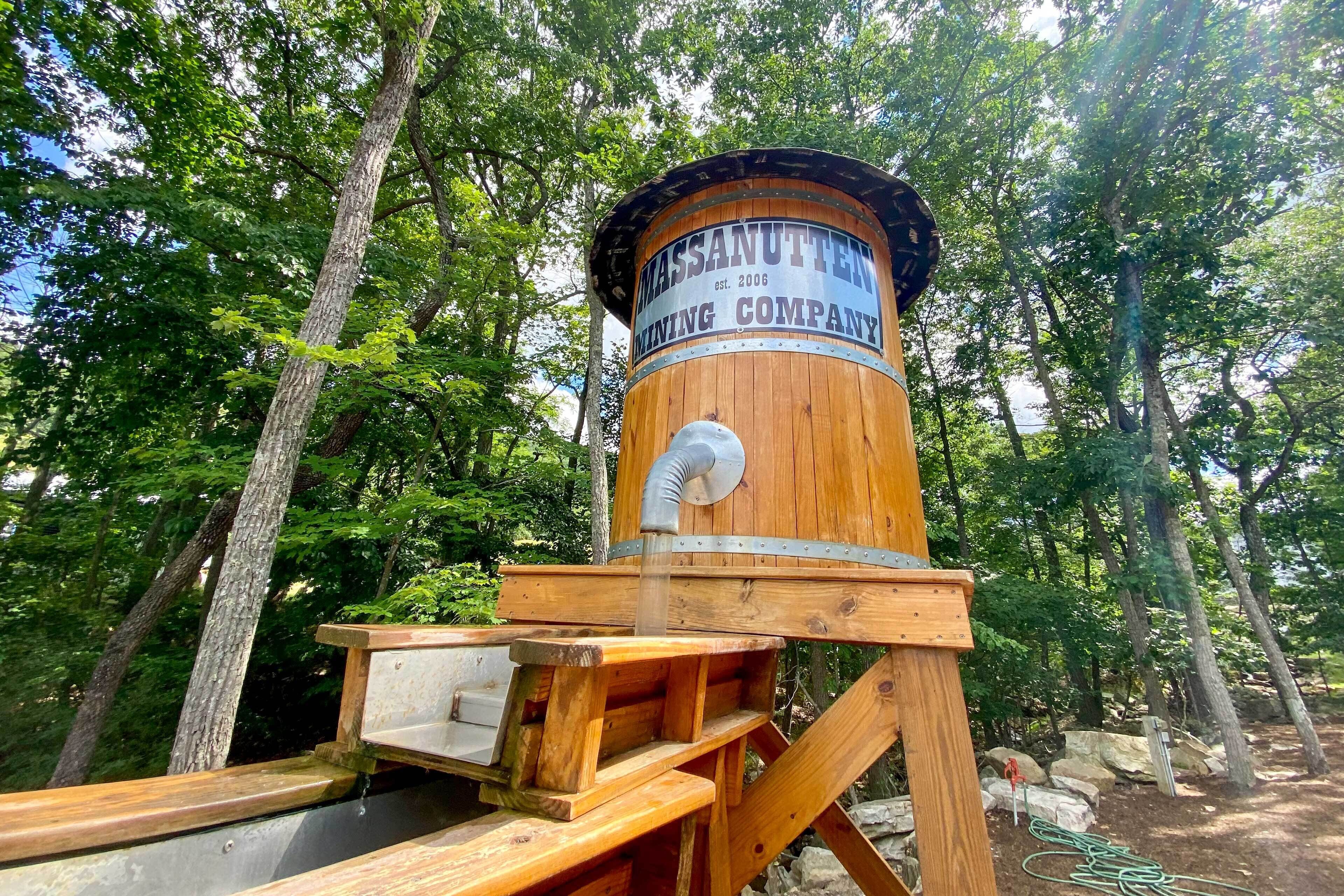A wooden water tower with a sign reading "Massanutten Mining Company" surrounded by trees.