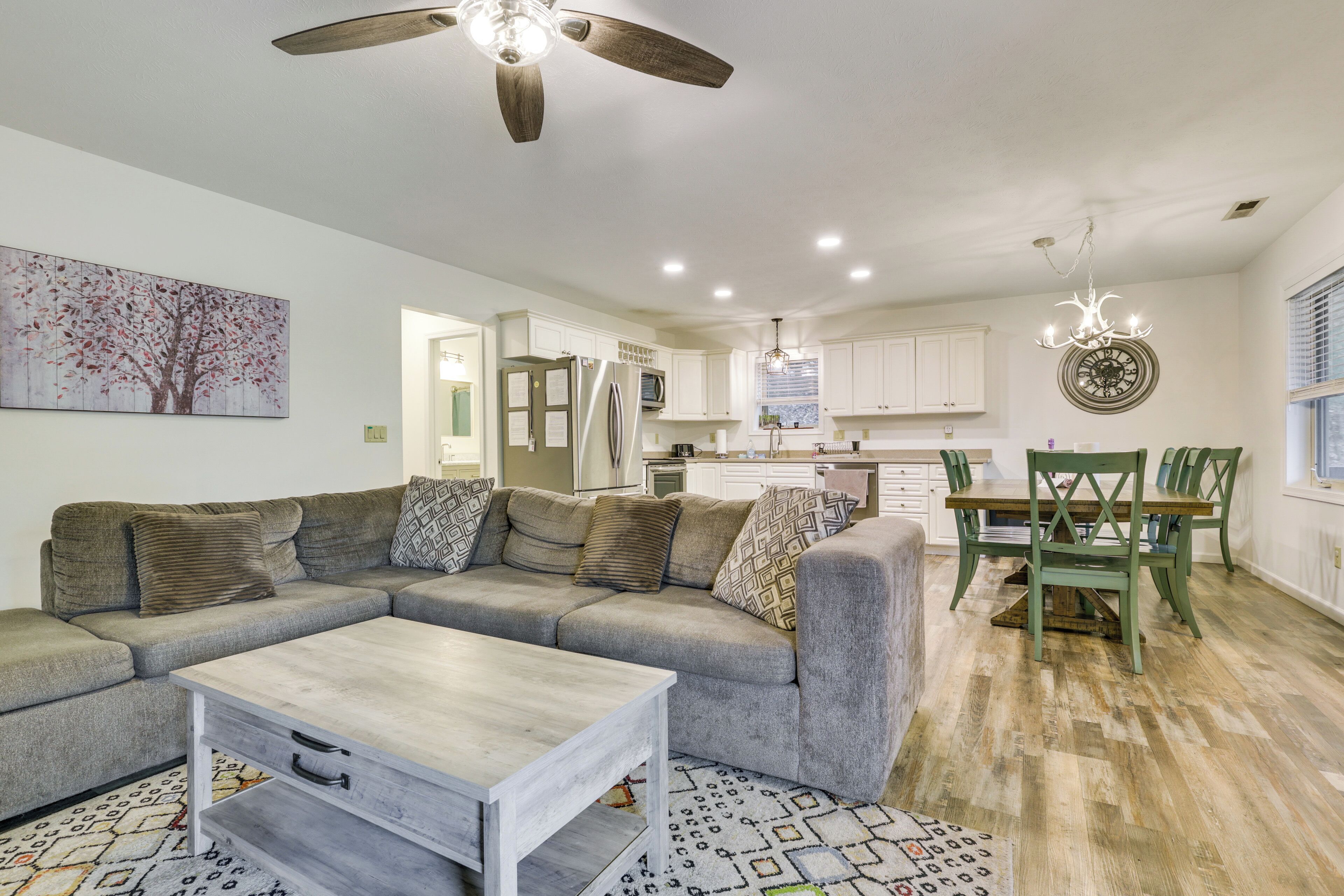 A modern living room with a sectional sofa, a coffee table, and a dining area with a table and chairs.