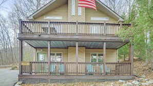 A two-story wooden cabin with a balcony, a porch with chairs, and an American flag. - Family Getaway < 2 Mi to Massanutten Ski Lodge! (McGaheysville)