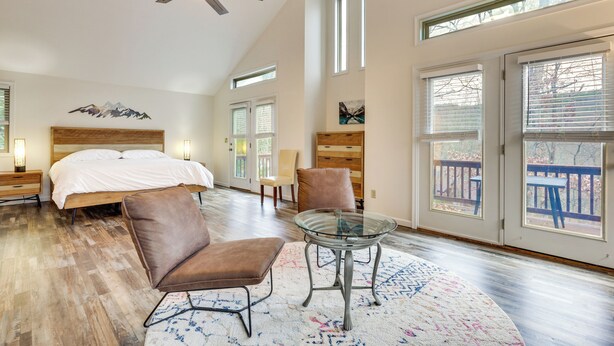A spacious bedroom with a large bed, a glass table, and a view of the outdoors through large windows. - Family Getaway < 2 Mi to Massanutten Ski Lodge! (McGaheysville)