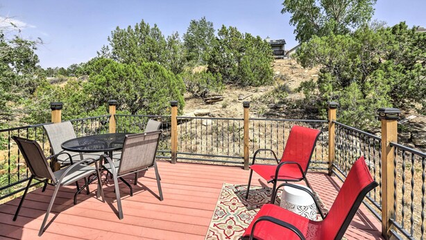 Une terrasse dotée de mobilier d’extérieur, d’un tapis à motifs et offrant une vue sur des arbres et un bâtiment en arrière-plan.