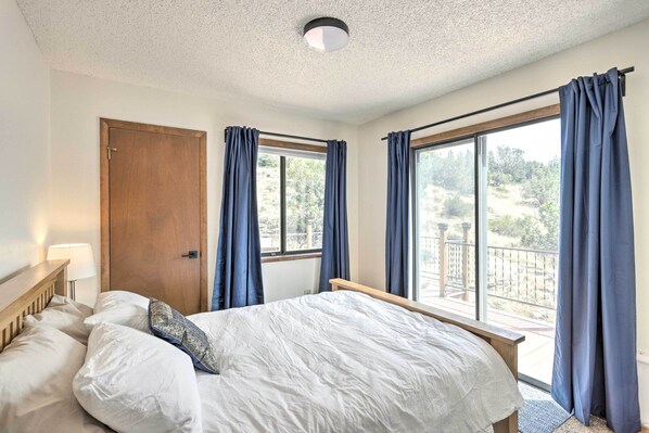 Un dormitorio con cama, una puerta de madera y una ventana con cortinas.