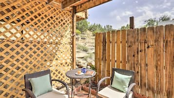 An outdoor patio with wicker furniture, a small round table, and a wooden fence.