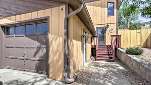 Un immeuble résidentiel doté d’un garage, d’une façade en bois et d’un petit porche avec des marches.