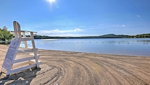 A beach with a signboard titled "BEACH RULES" and a wooden chair. - Deck & Resort Amenities: Arrowhead Lake Home! (Pocono Lake)