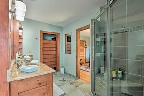 Um banheiro com toucador de madeira, box de vidro e piso ladrilhado.