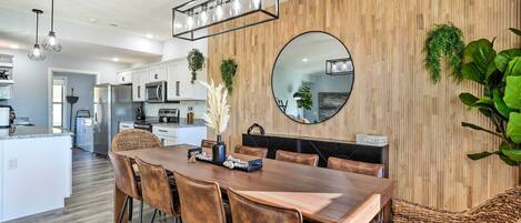 A modern kitchen with white cabinets, a wooden island, and a dining area with a wooden table and chairs.