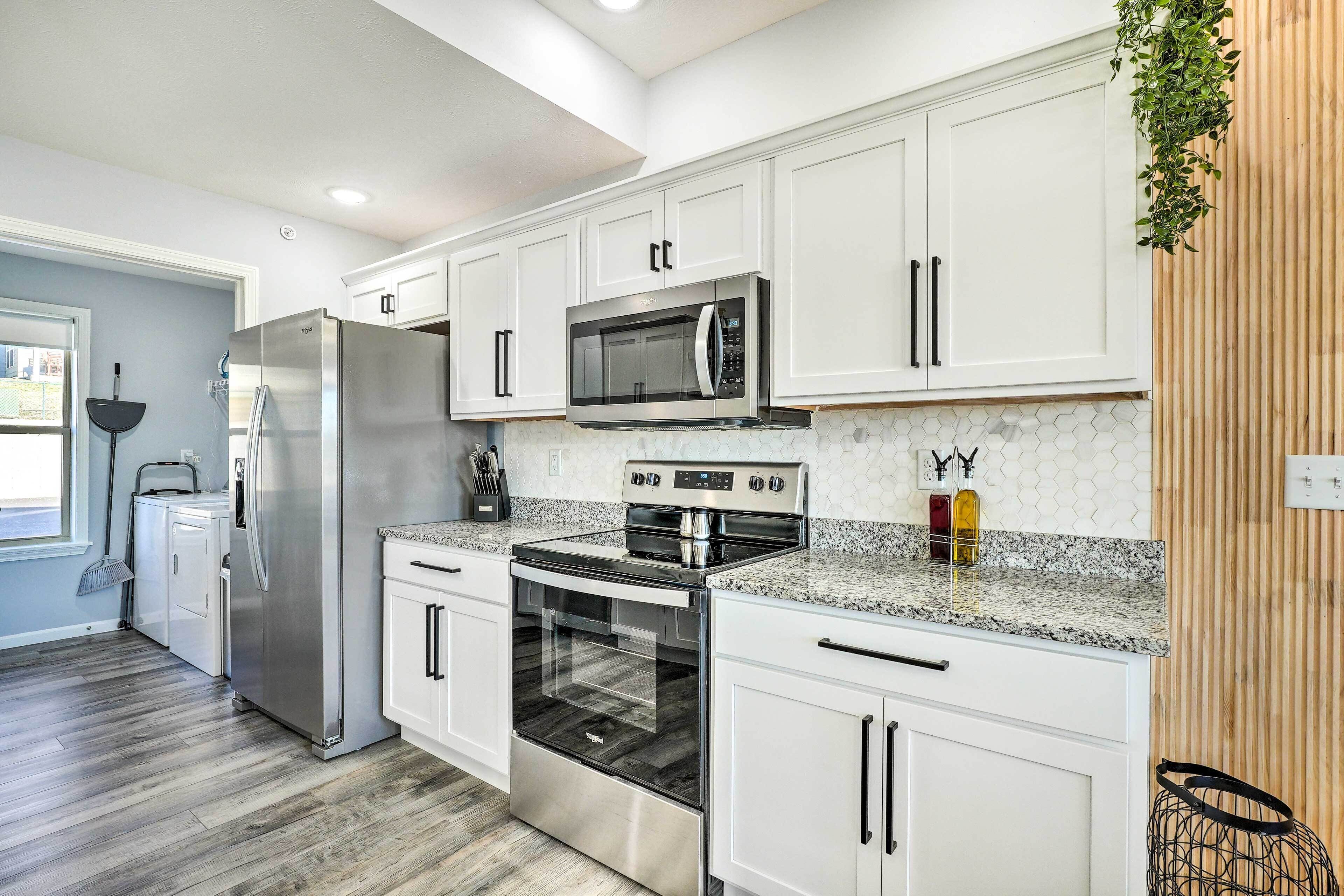 A modern kitchen with white cabinets, stainless steel appliances, and a granite countertop.