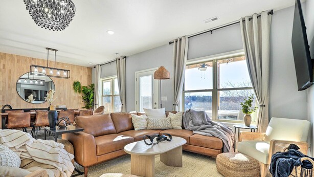 A modern living room with a brown leather sofa, a round coffee table, and a large mirror with lights. - Reeds Spring Condo ~ 3 Mi to Silver Dollar City! (Branson West)