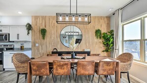 A dining area with a wooden wall, a round mirror, and a hanging light fixture. - Reeds Spring Condo ~ 3 Mi to Silver Dollar City! (Branson West)