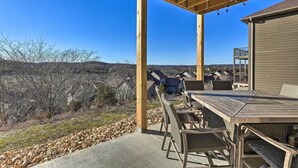 An outdoor patio with a wooden table and chairs, a concrete floor, and a view of a hilly landscape. - Reeds Spring Condo ~ 3 Mi to Silver Dollar City! (Branson West)