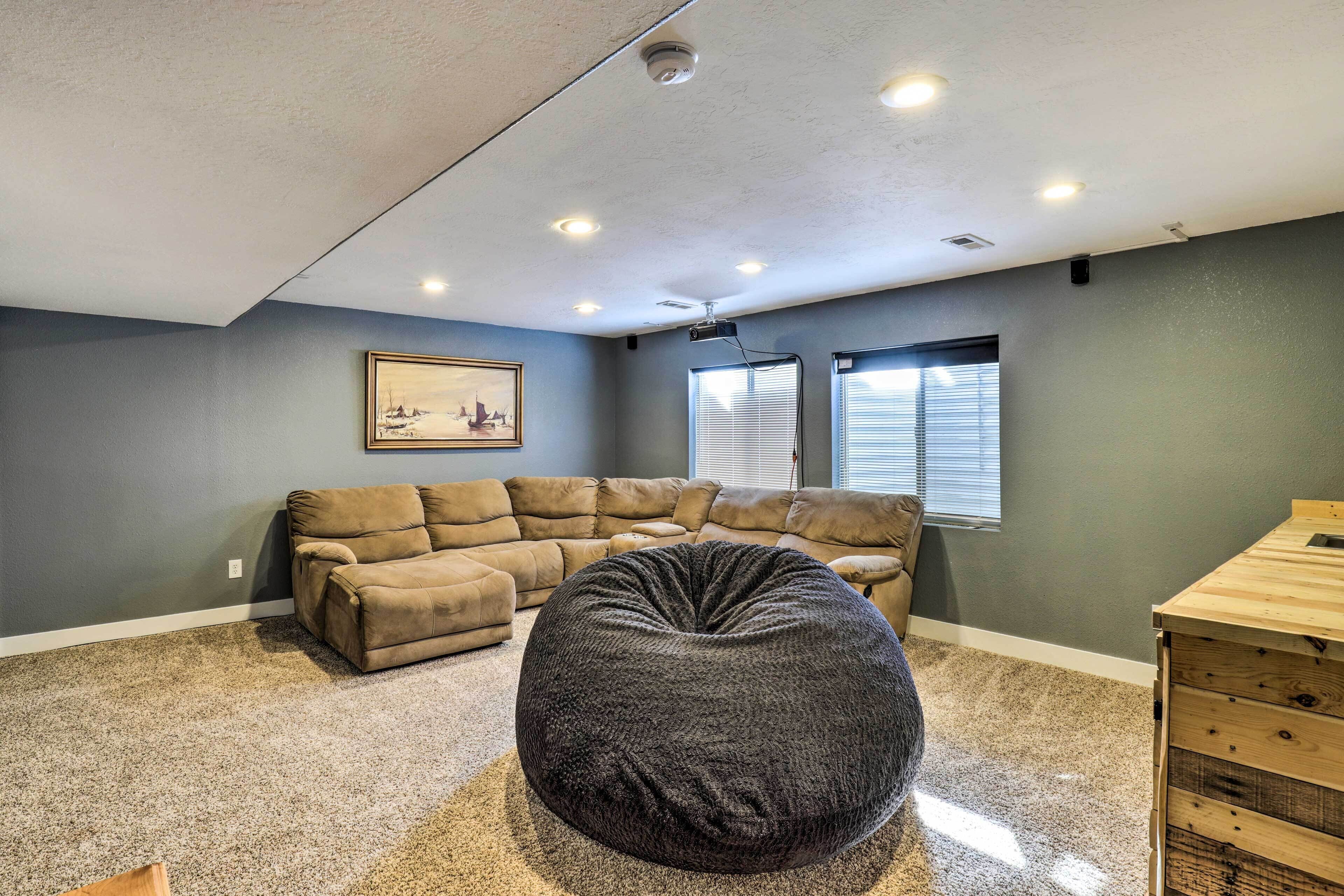 A living room with a sectional sofa, a round bean bag, and a wooden side table.