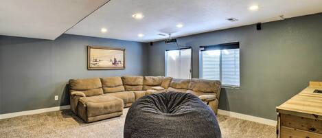 A living room with a sectional sofa, a round bean bag, and a wooden side table.