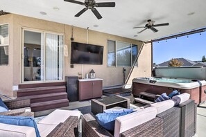 Une terrasse extérieure aménagée avec des meubles en osier, un jacuzzi et des ventilateurs de plafond.