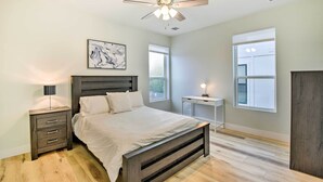 A bedroom with a bed, bedside table, lamp, ceiling fan, and artwork on the wall. - Walk to Tcu: Fort Worth Retreat w/ Balcony! (Fort Worth)