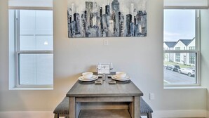 A dining area with a gray table, two white bowls, and a cityscape painting above. - Walk to Tcu: Fort Worth Retreat w/ Balcony! (Fort Worth)