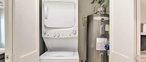 A compact laundry room with a washing machine, dryer, and water heater.