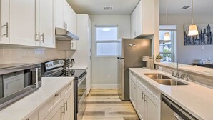 A modern kitchen with white cabinets, stainless steel appliances, and a large window. - Walk to Tcu: Fort Worth Retreat w/ Balcony! (Fort Worth)