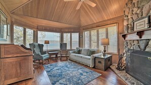 A cozy living room with a wooden ceiling, stone wall, and large windows with blinds. - Waterfront Suttons Bay: Wine Trail, Pickleball Ct (Suttons Bay)