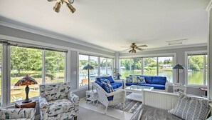 Une véranda dotée de grandes fenêtres, d’un ventilateur de plafond et offrant une vue sur un lac.