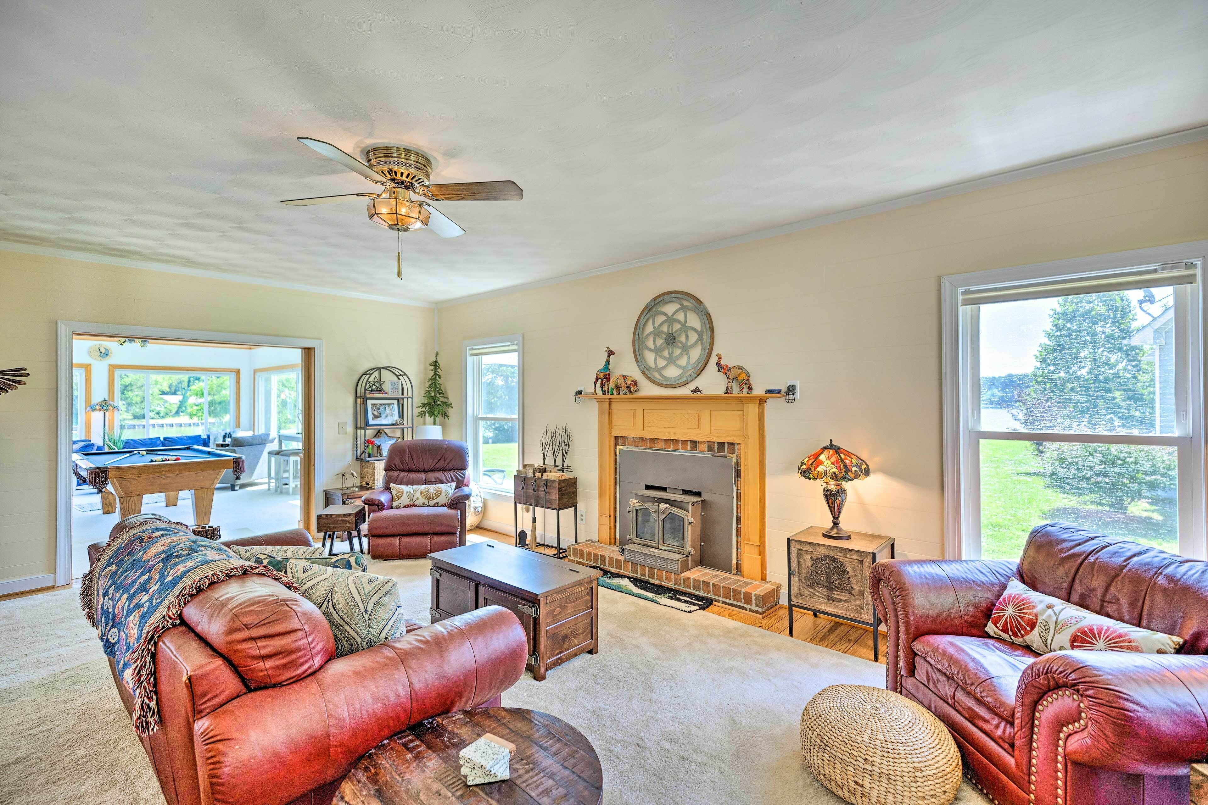 A spacious living room with leather sofas, a fireplace, and a pool table.