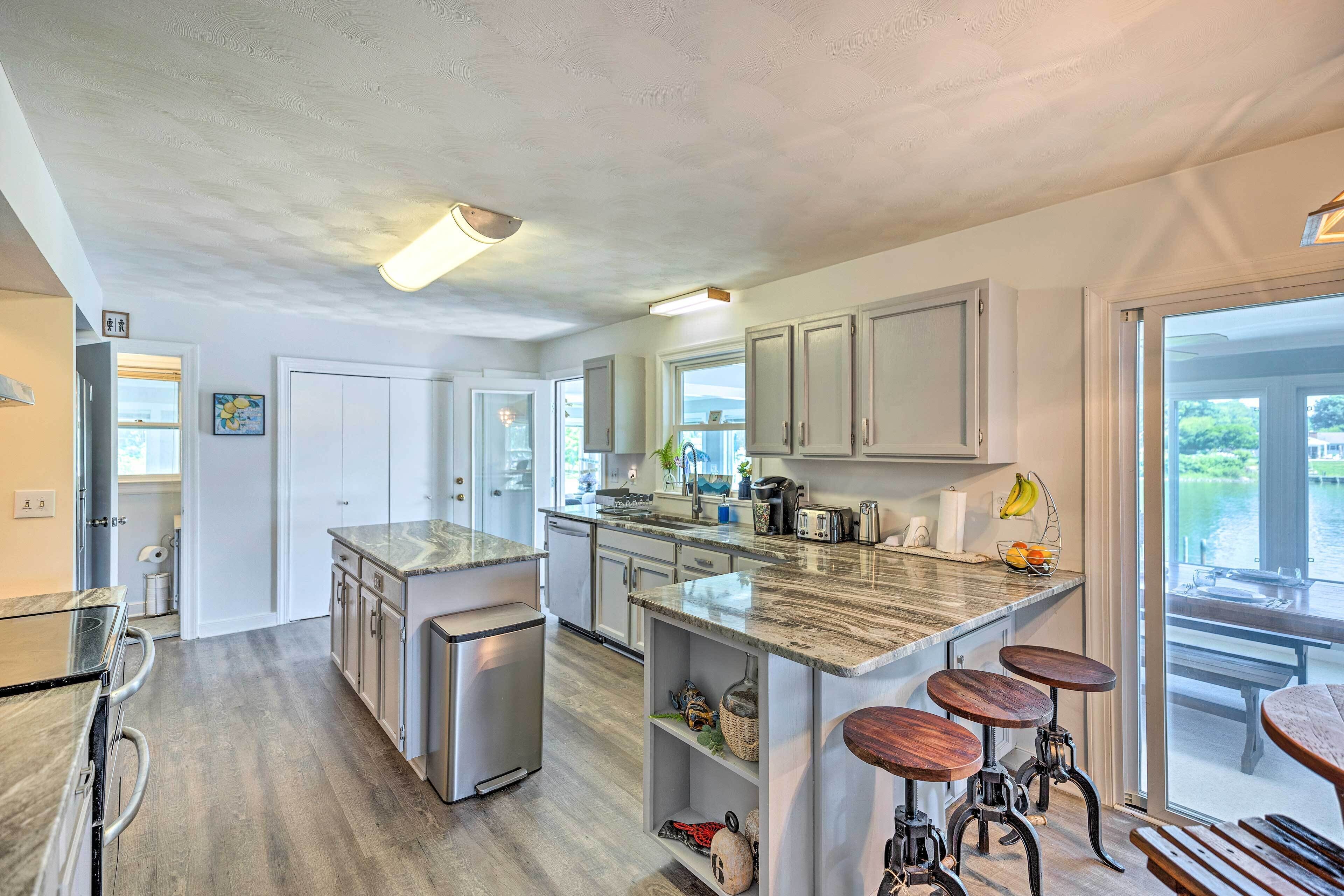 A modern kitchen with a large island, stainless steel appliances, and a view of the outdoors.