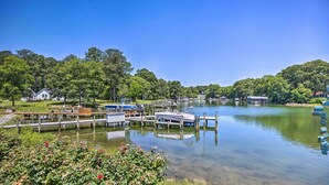 Une jetée au bord du lac avec des bateaux, un kiosque et une maison en arrière-plan.