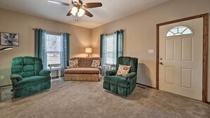 A living room with a ceiling fan, two green armchairs, a brown sofa, and a door with a window. - Historical West Mineral Escape w/ Porch! (West Mineral)