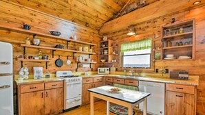 Una cocina rústica con paredes de madera, una isla central y diversos electrodomésticos.