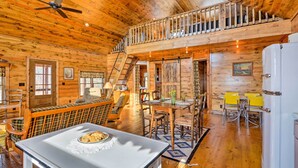 Una cabaña amplia con comedor, cocina y habitación en entrepiso.