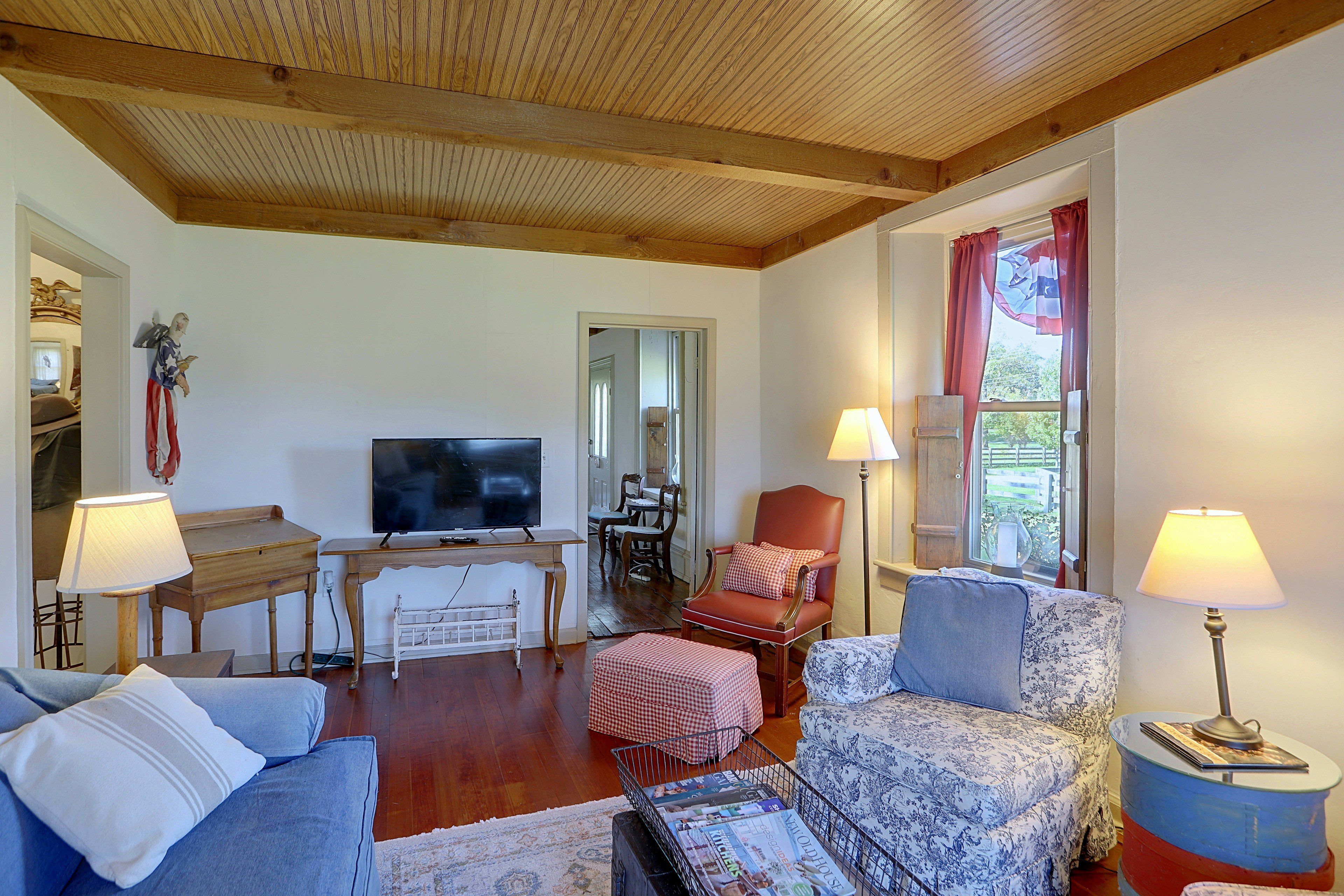 A living room with a television, seating, and a window with curtains.
