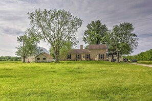 Ein zweistöckiges Haus mit Ziegelaußenwand, umgeben von einer großen, grünen Wiese und Bäumen.
