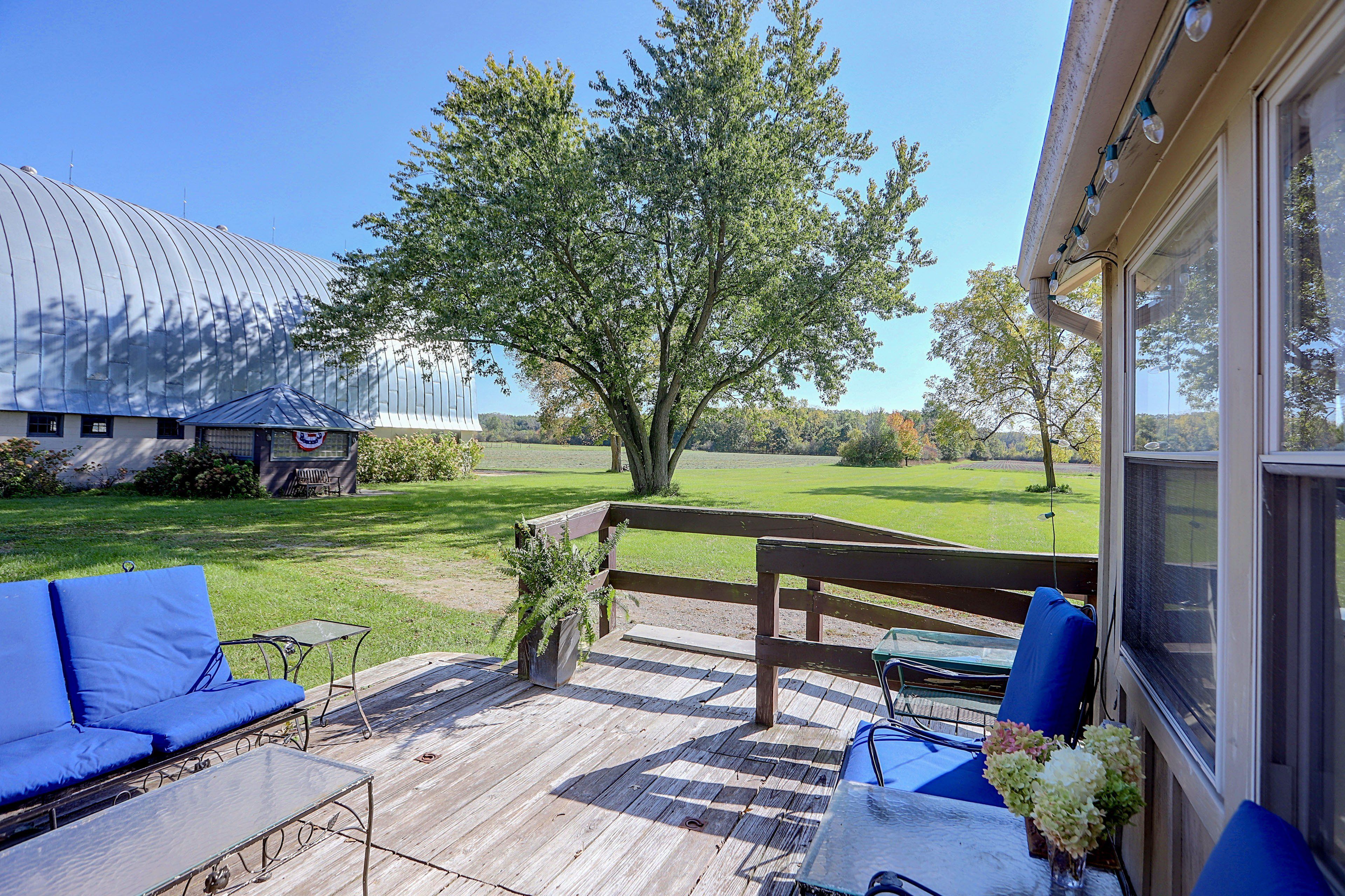A covered outdoor patio with a wooden deck, a blue sofa, and a table.