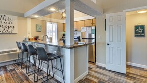 A kitchen with a central island, bar stools, a refrigerator, and a door with a sign. - Walk to Lake: Osage Beach Home w/ Grill! (Osage Beach)